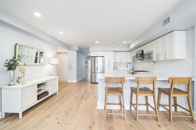 833 Willow Ave Unit 2, Hoboken, NJ 07030 - kitchen with stainless steel appliances, a peninsula, light wood-style flooring, white cabinets, and recessed lighting