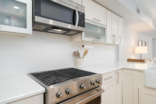 833 Willow Ave Unit 2, Hoboken, NJ 07030 - kitchen with stainless steel appliances, backsplash, glass insert cabinets, white cabinets, and light stone counters