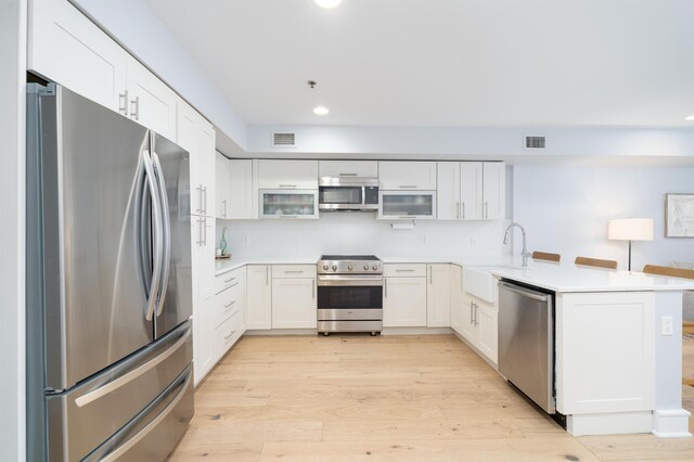 833 Willow Ave Unit 2, Hoboken, NJ 07030 - kitchen featuring appliances with stainless steel finishes, a peninsula, light wood-style flooring, recessed lighting, and white cabinetry