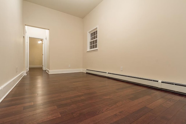 unfurnished room featuring dark wood-type flooring and a baseboard heating unit