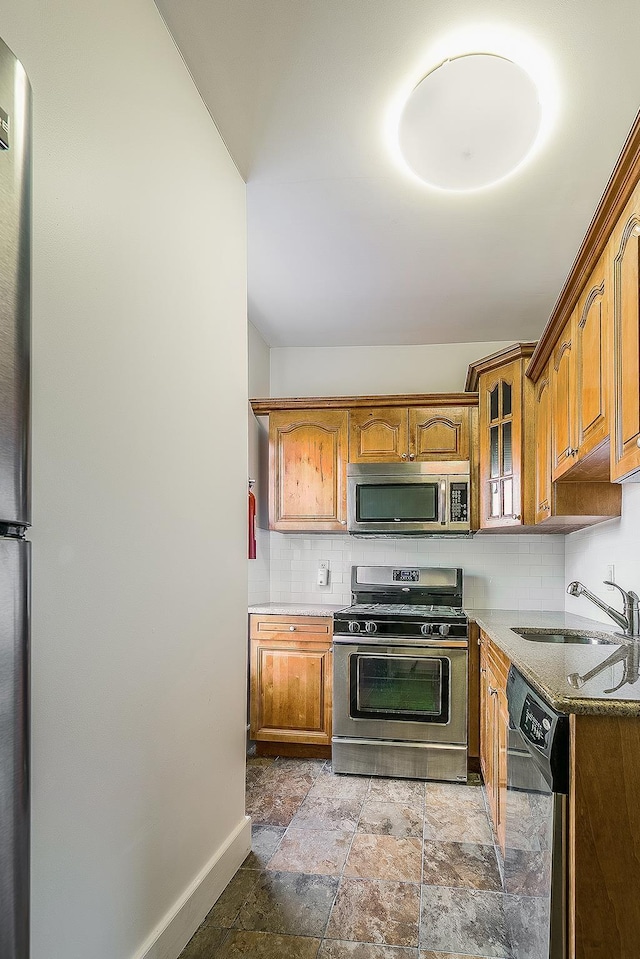 kitchen featuring sink, stainless steel appliances, stone counters, and tasteful backsplash