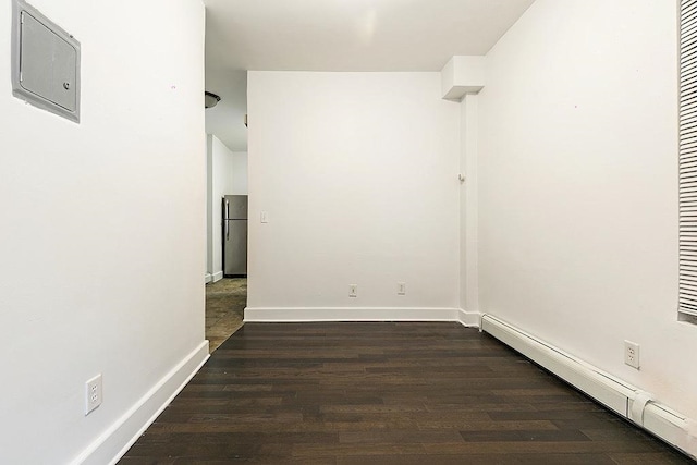 spare room featuring baseboard heating and dark hardwood / wood-style floors