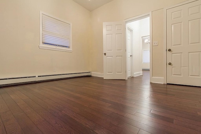 empty room featuring dark wood-type flooring, vaulted ceiling, and a baseboard heating unit