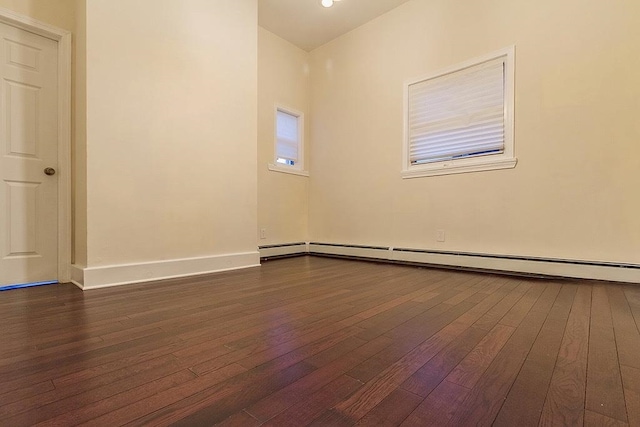 spare room with dark hardwood / wood-style flooring and a baseboard heating unit