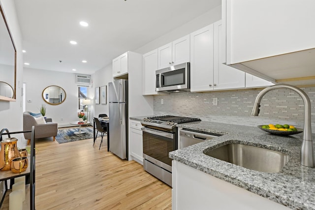 110 Washington St Unit 8, Hoboken, NJ 07030 - kitchen featuring appliances with stainless steel finishes, backsplash, light wood-style flooring, light stone countertops, and white cabinets