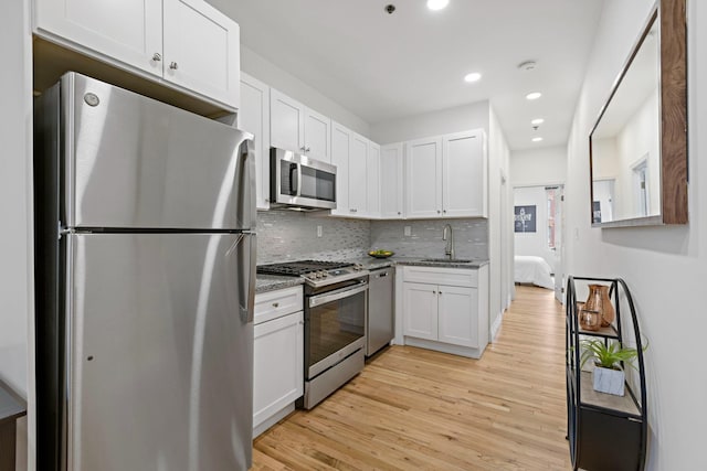 110 Washington St Unit 8, Hoboken, NJ 07030 - kitchen with appliances with stainless steel finishes, white cabinets, light wood-style floors, light stone counters, and backsplash