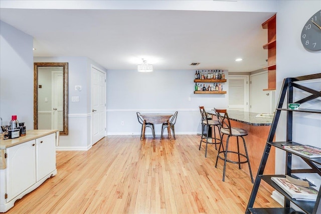 dining area with bar area and light wood-type flooring