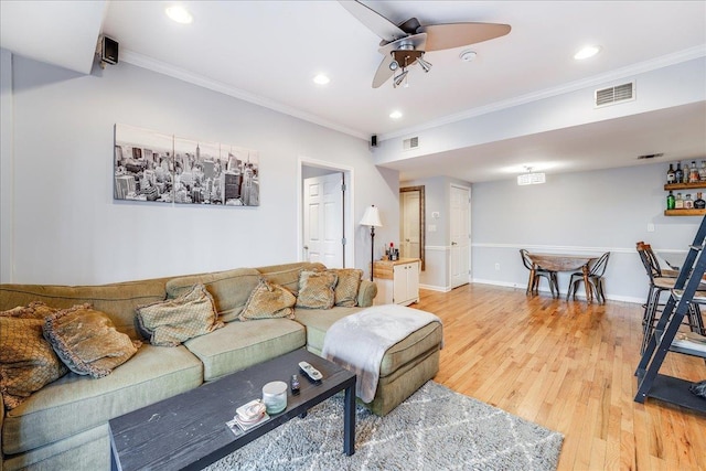 living room with crown molding, wood-type flooring, and ceiling fan