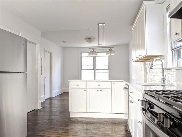 149 37th St, Union City, NJ 07087 - kitchen featuring stainless steel appliances, white cabinetry, a peninsula, a sink, and light countertops