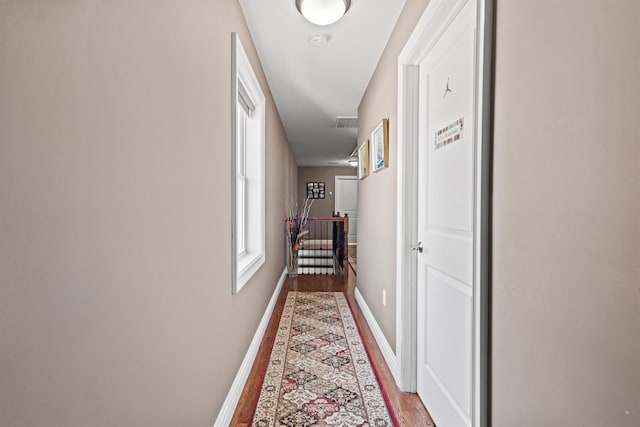 corridor featuring baseboards, visible vents, and wood finished floors