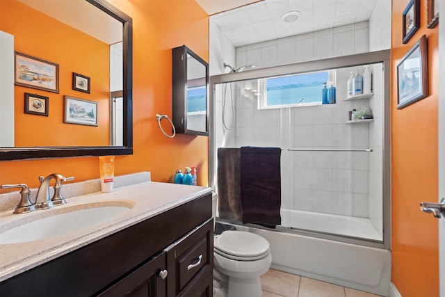 bathroom featuring toilet, combined bath / shower with glass door, tile patterned flooring, and vanity
