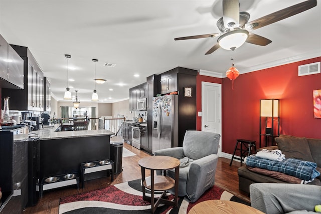 living area featuring visible vents, a ceiling fan, crown molding, and wood finished floors