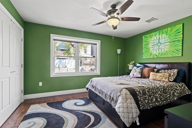 bedroom featuring baseboards, a ceiling fan, wood finished floors, and visible vents
