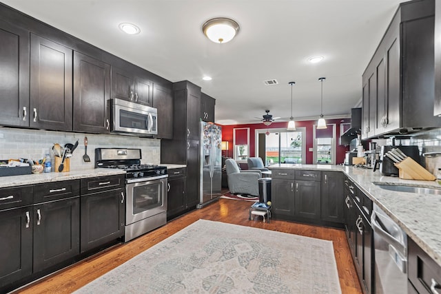 kitchen with visible vents, decorative backsplash, open floor plan, a ceiling fan, and stainless steel appliances