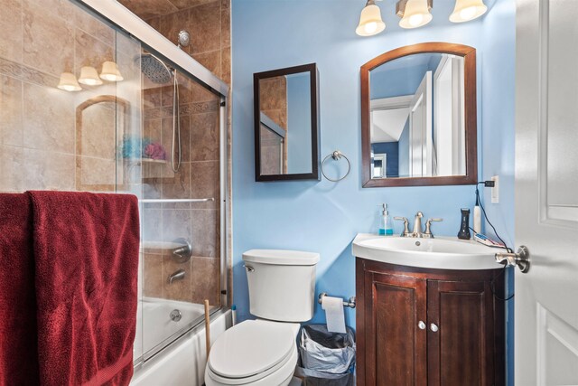 full bath with vanity, toilet, and shower / bath combination with glass door