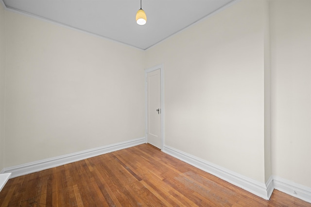 spare room with baseboards and wood finished floors