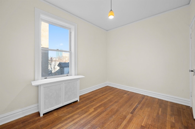 spare room with radiator, dark wood finished floors, and baseboards