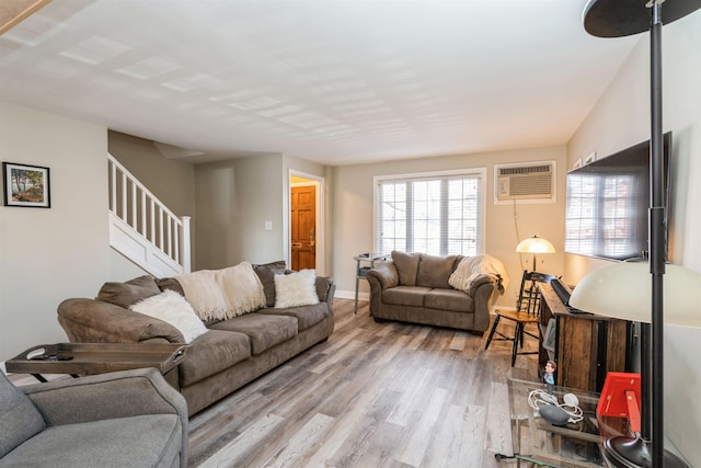 living area featuring stairway, a wall unit AC, wood finished floors, and baseboards