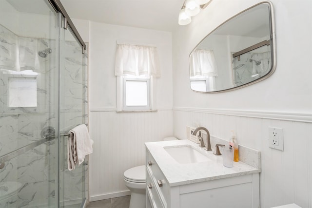 full bathroom with a marble finish shower, wainscoting, vanity, and toilet