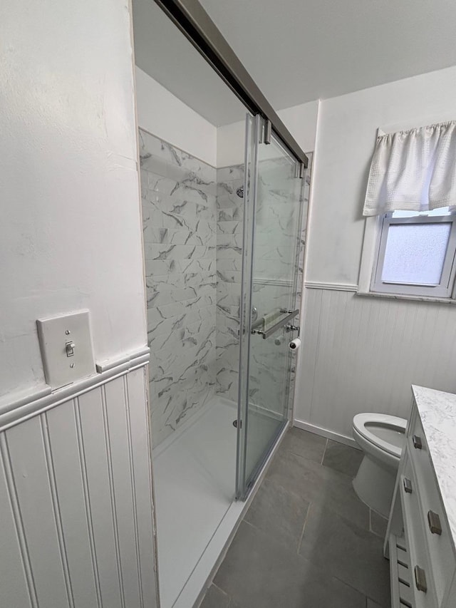 full bathroom featuring a wainscoted wall, toilet, a marble finish shower, and vanity