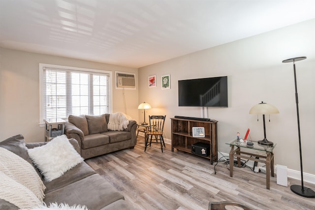 living room featuring a wall mounted air conditioner, baseboards, and wood finished floors