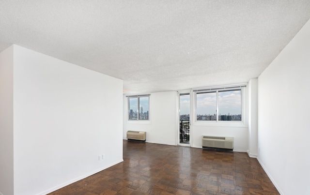 empty room featuring a textured ceiling, an AC wall unit, and plenty of natural light