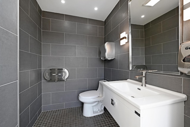 bathroom featuring tile patterned floors, vanity, toilet, and tile walls