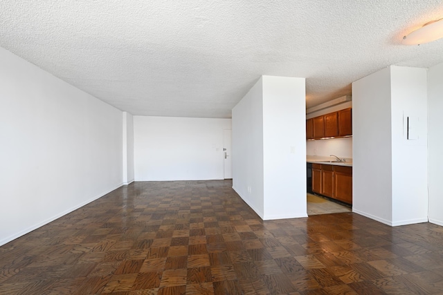 spare room with dark parquet flooring, a textured ceiling, and sink