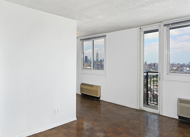 spare room with a wall mounted AC, plenty of natural light, and a textured ceiling