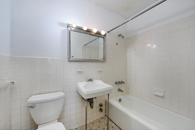 full bathroom with tile patterned flooring, tiled shower / bath combo, toilet, a textured ceiling, and tile walls