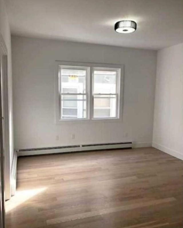 24 E 49th St, Bayonne, NJ 07002 - spare room with wood finished floors, baseboard heating, and baseboards