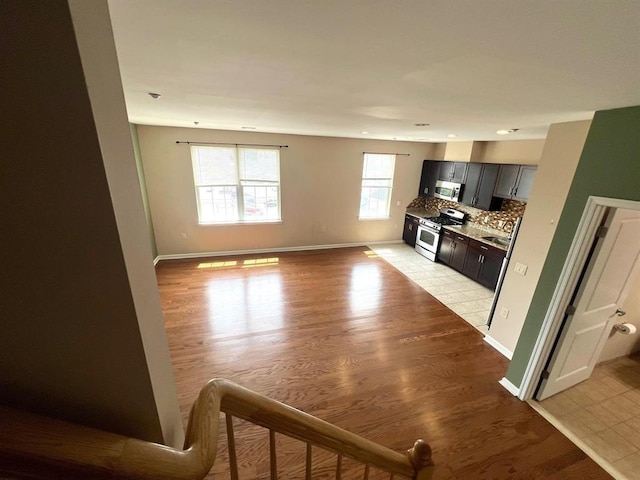 interior space featuring tasteful backsplash, stainless steel appliances, sink, and light wood-type flooring