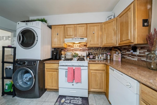 kitchen featuring stone countertops, light tile patterned floors, white appliances, stacked washer / dryer, and decorative backsplash