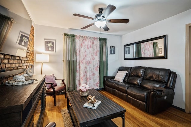 living room featuring a brick fireplace, light wood-type flooring, and ceiling fan