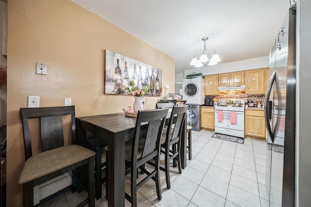 dining room with stacked washer and dryer, light tile patterned flooring, and an inviting chandelier