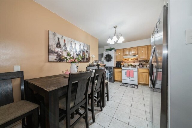 dining area with stacked washer and dryer, a notable chandelier, and light tile patterned floors