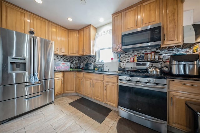 kitchen with stainless steel appliances, sink, light tile patterned floors, backsplash, and dark stone countertops