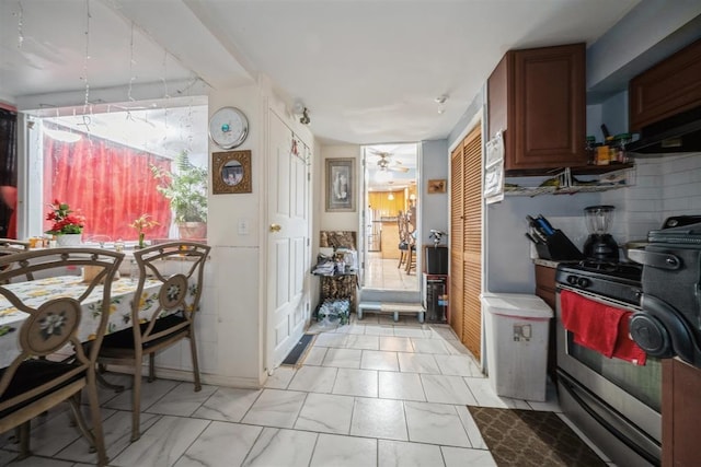 kitchen featuring backsplash, stainless steel gas range oven, and ceiling fan