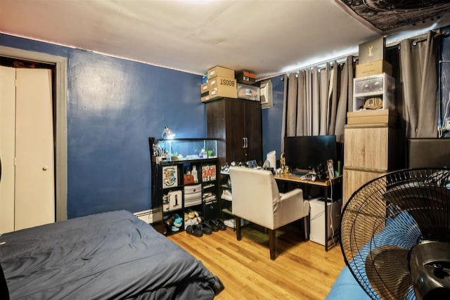 bedroom featuring a baseboard heating unit and light wood-type flooring