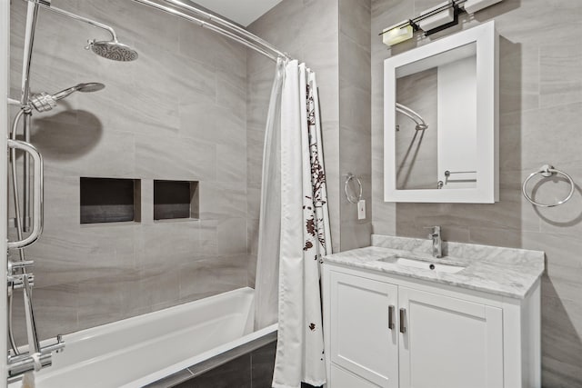 bathroom featuring tile walls, tiled shower / bath combo, and vanity