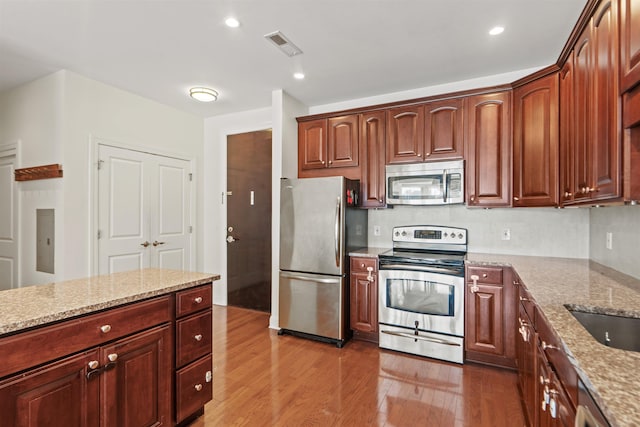 kitchen featuring light stone counters, visible vents, wood finished floors, and stainless steel appliances