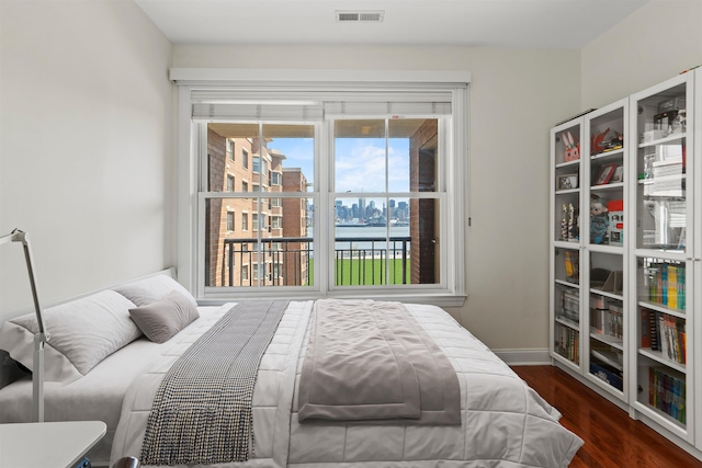 bedroom with wood finished floors, visible vents, baseboards, and multiple windows