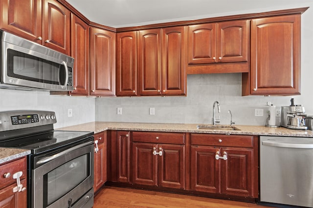 kitchen with decorative backsplash, stainless steel appliances, light stone countertops, and a sink