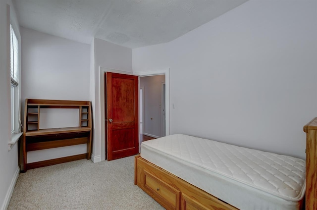 bedroom with baseboards and light carpet