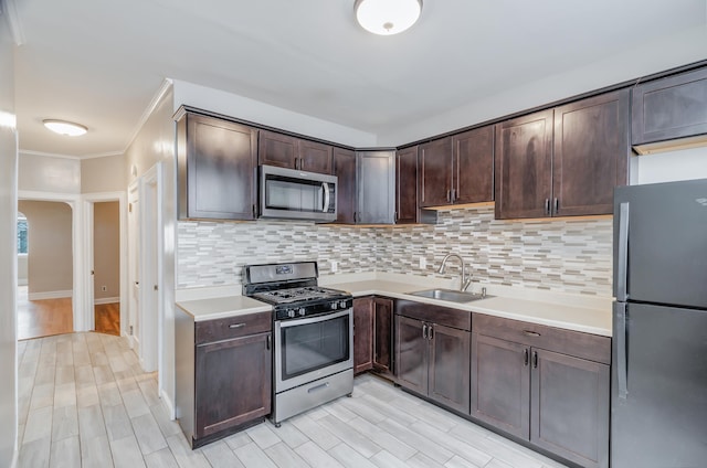 kitchen featuring a sink, stainless steel appliances, light countertops, dark brown cabinetry, and tasteful backsplash