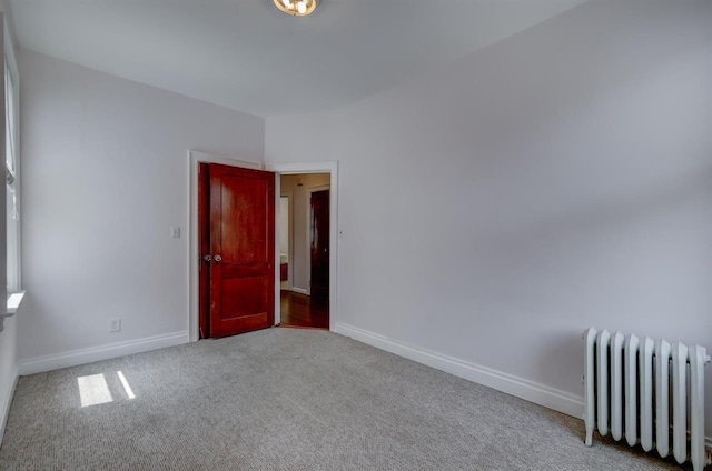 unfurnished room with radiator, baseboards, and carpet floors