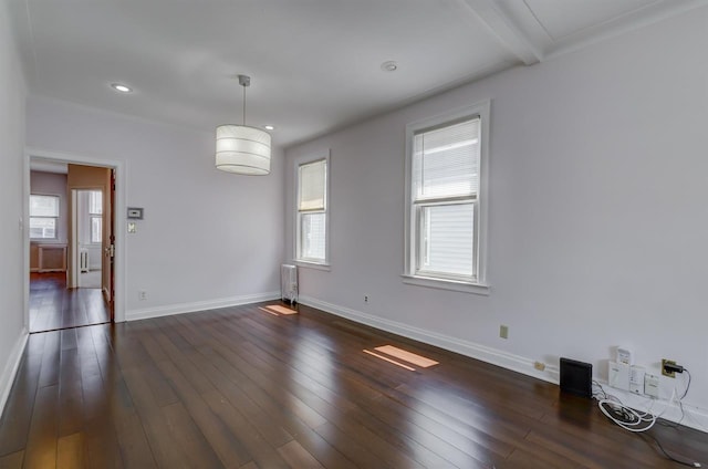 empty room featuring a healthy amount of sunlight, radiator, dark wood-type flooring, and baseboards