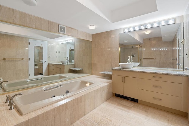 full bath featuring visible vents, vanity, a whirlpool tub, a tile shower, and tile walls