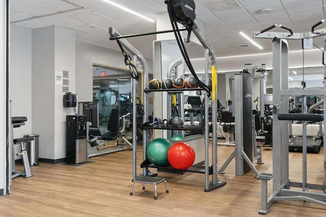 exercise room with a drop ceiling and wood finished floors