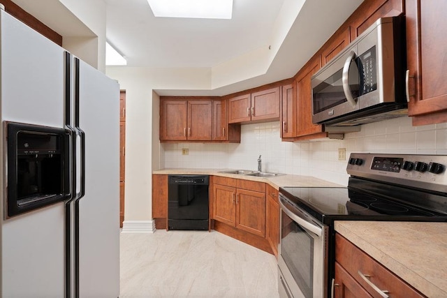 kitchen with brown cabinetry, a sink, light countertops, appliances with stainless steel finishes, and backsplash